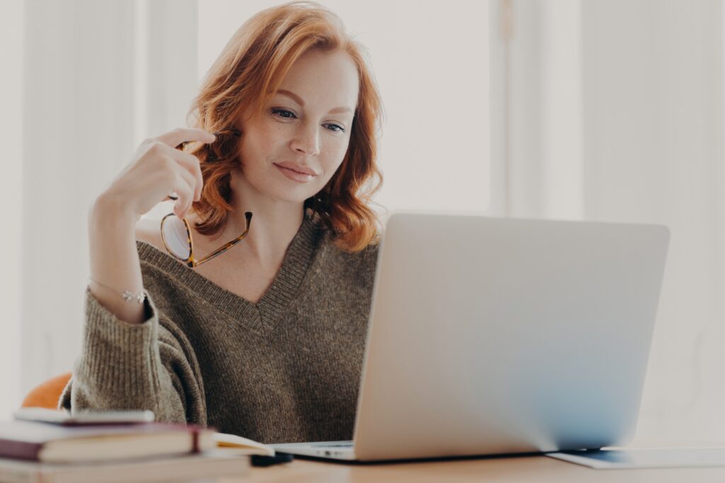 female student reads information and checks data, focused at laptop screen